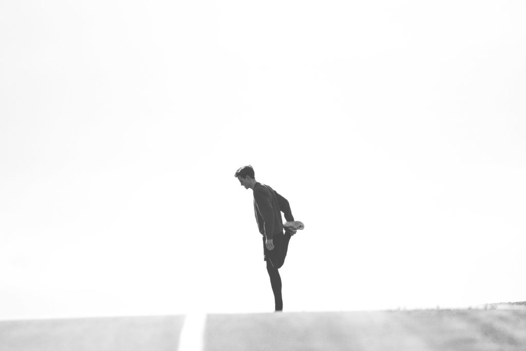 Man outside, knee bent stretching - Achieving your Health Goals blog post
