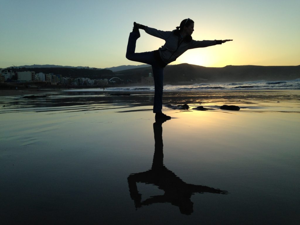 Woman in yoga position on beach - The all over sync…mind and body blog post