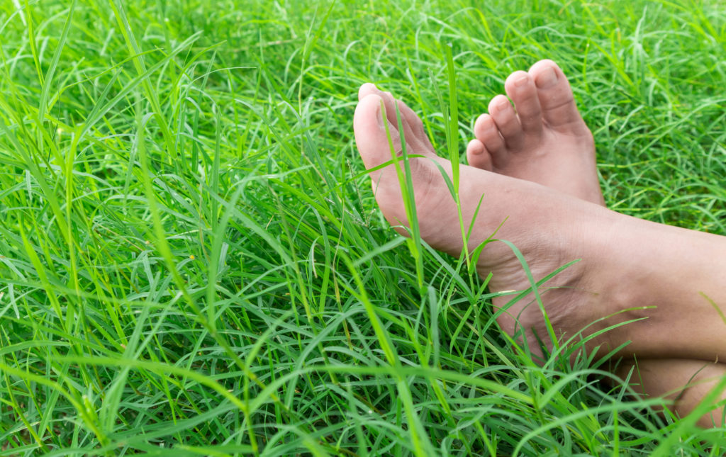 Feet of person sitting in grass - Are Orthotics a Medical Gimmick? blog post
